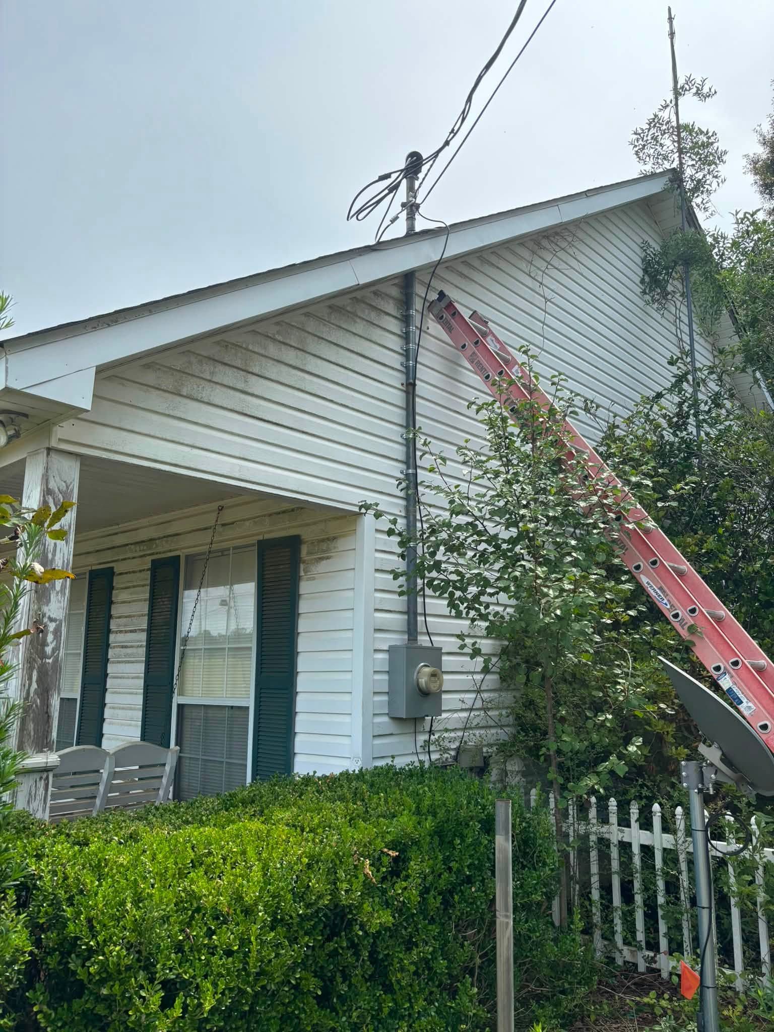 Ladder set against a white vinyl-sided house during the repair